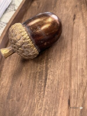 Brązowo-złoty żołądź dekoracyjny o wymiarach 12,5 × 7 × 7 cm to niewielka ozdoba do jesiennych aranżacji stołu, komody i półki. Połyskujący, zaokrąglony korpus kontrastuje z fakturowaną czapeczką w odcieniu postarzanego złota. Możesz wyeksponować go samodzielnie lub włączyć do kompozycji z liśćmi, grzybkami i lampionem LED.